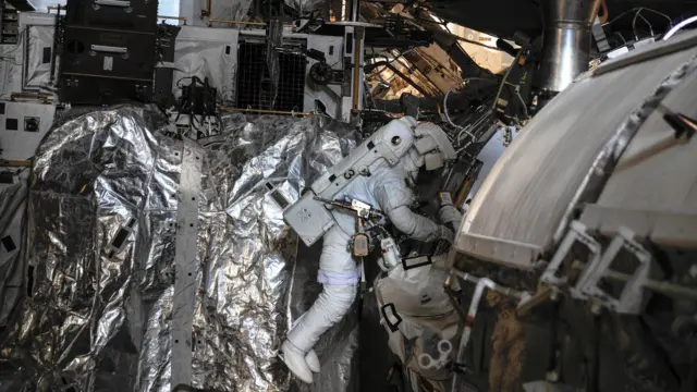 Um astronauta segurando uma nave espacial enquanto realiza manutenção.