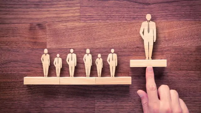 Una persona eligiendo una figurita de madera dentro de un grupo