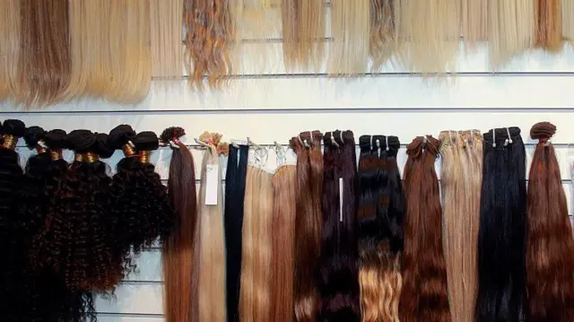 Bundles of hair extensions tied together and displayed for sale.