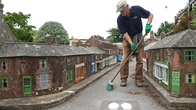इंग्लैड के विमबॉर्न मॉडल टाउन और गार्डन में सफाई करता एक व्यक्ति.