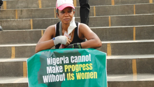 A woman with a poster saying: "Nigeria cannot make progress without her women" takes part in a protest in Ikeja, Lagos in Nigeria - Tuesday 8 March 2022