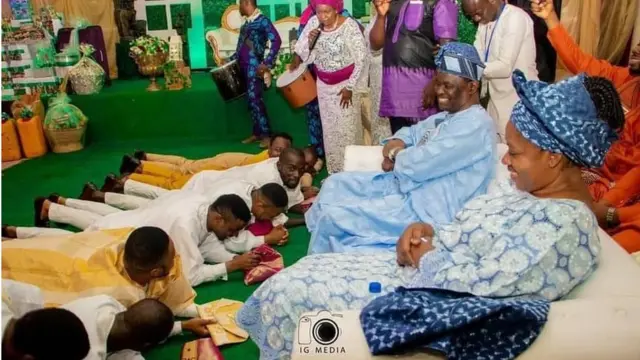 Ọkọ iyawo, Lawrence, ati awọn ọrẹ rẹ re e to n dọbalẹ niwaju awọn obi iyawo rẹ.