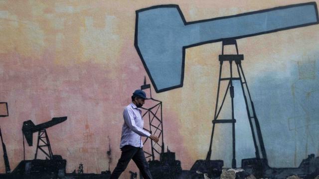 Un hombre pasa por delante de un graffiti de petróleo