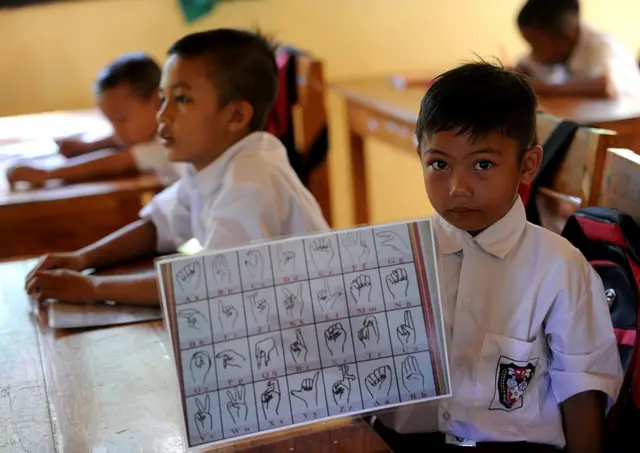 Niño con un tablero de lengua de señas.