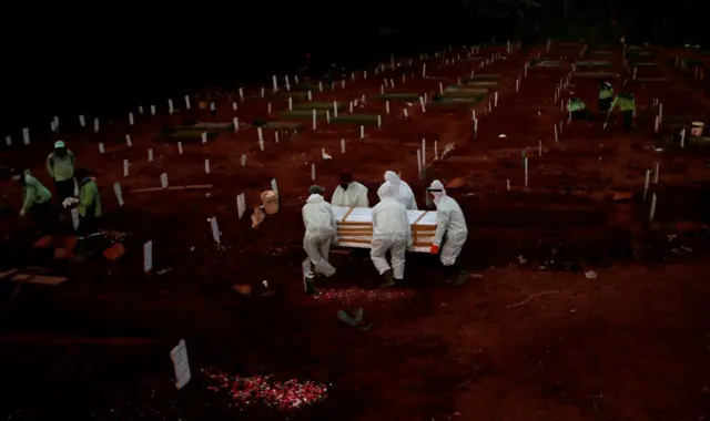 Workers carry a coffin in a cemetery complex for coronavirus victims in Jakarta, Indonesia, 22 April 2020