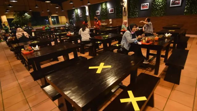 Pengunjung menyantap hidangan di antara meja yang diberi tanda silang di salah satu restoran di Srengseng Sawah, Jakarta Selatan, Kamis (09/04).