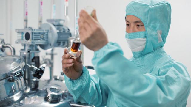 Homem asiático observa um líquedobet 365 no iphoneuma pipeta no laboratório