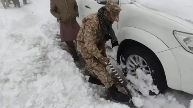 பனியிலிருந்து காரை மீட்கும் வீரர்