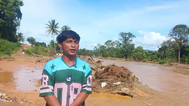 Arman Zebua berada di pinggir sungai yang sudah porak-poranda.