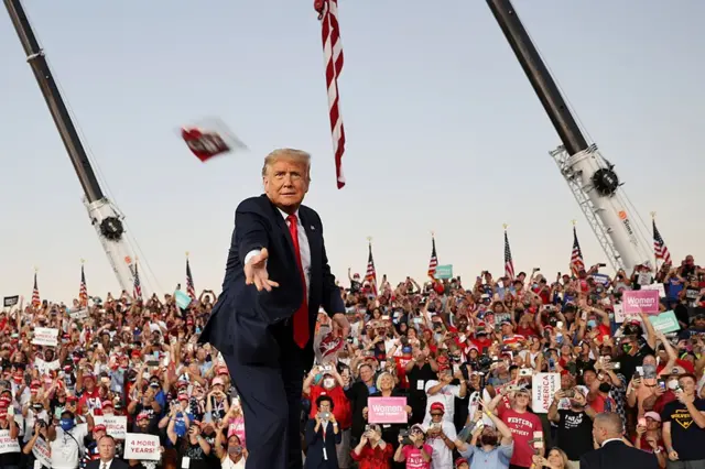 US President Donald Trump throws a face mask into the crowd