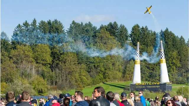 competencia de aviones de Red Bull que deja una estela de humo mientras pasa a través de 2 conos.