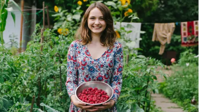 Mujer con frutas del bosque en un jardín.
