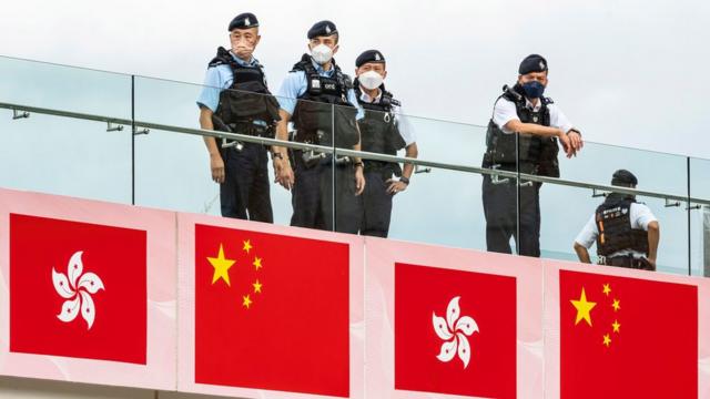 中国香港特区成立25周年日一群身穿防刺背心警员在九龙尖沙咀海旁高台上严密注视地面活动（1/7/2022）