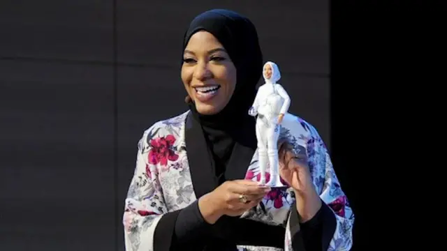 Ibtihaj Muhammad segura Barbie embetano 100 rodadas grátishomenagem, ambas vestindo um hijab