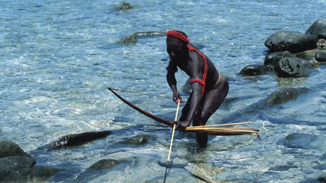 A Jarawa man catching fish with bow and arrow