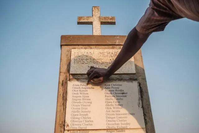 A man points to names etched on a memorial.