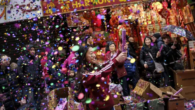 A woman pops confetti during a cultural festival to mark the first day of the Lunar New Year in Chinatown neighborhood in Manhattan, February 16, 2018 in New York City.