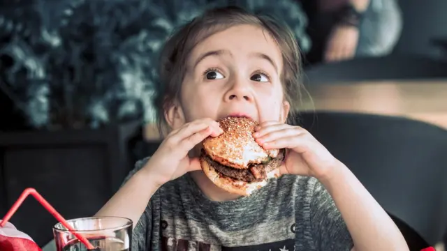 بچهای در حال خوردن همبرگر