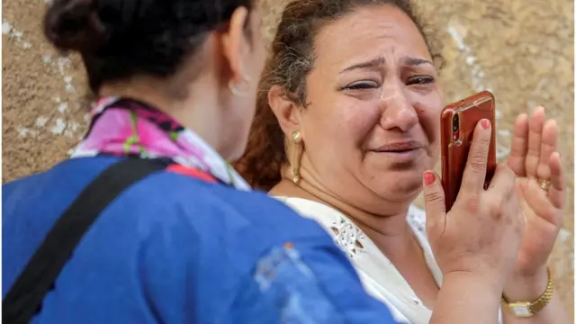 امرأة يبدو عليها التأثر لدى مشاهدتها صور الحادث.