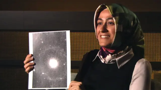 La joven astrofísca Burcin Mutlu-Pakdil con una imagen de la galaxia que descubrió