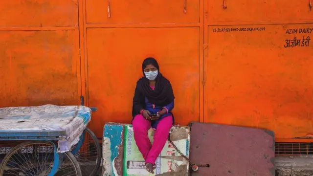 Una mujer india con una mascarilla en una calle desierta.