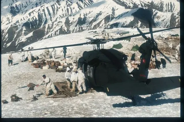 یک هلیکوپتر بر زمین نشسته و در حال پیاده کردن سربازها روی یک کوه است