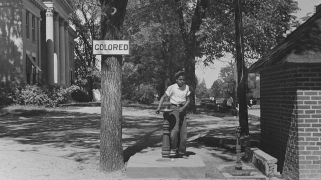 1938年，北卡罗来纳州一处有色人种使用的公共水池，树上挂着的牌子写着"有色"。