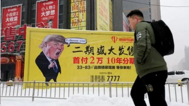 ચીનના શેનઝયાંગમાં ટ્રમ્પના કાર્ટૂન પાસેથી પસાર થઈ રહેલો યુવક