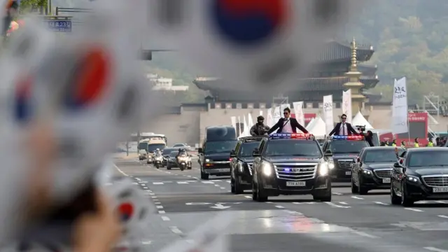 People wave South Korean flags as a convoy transporting South Korean President Moon Jae-in leaves the Presidential Blue House for the inter-Korean summit in Seoul, South Korea, April 27, 2018