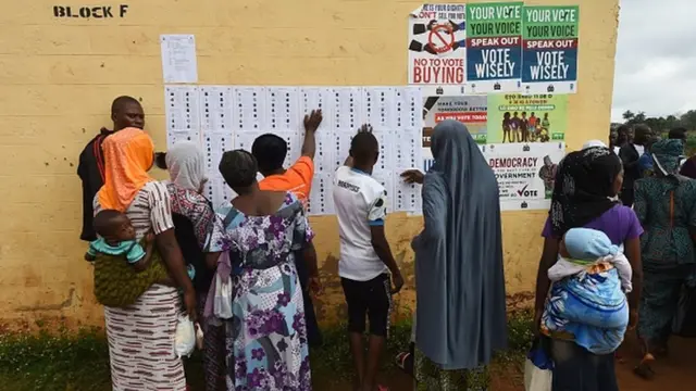 Wasu mata na duba sunayensu a kusa da wata rumfar zabe