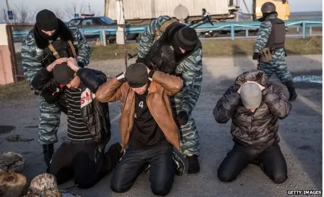 Milicianos pro-rusos revisan a unos transeuntes en un puesto de control en la entrada a la península de Crimea.