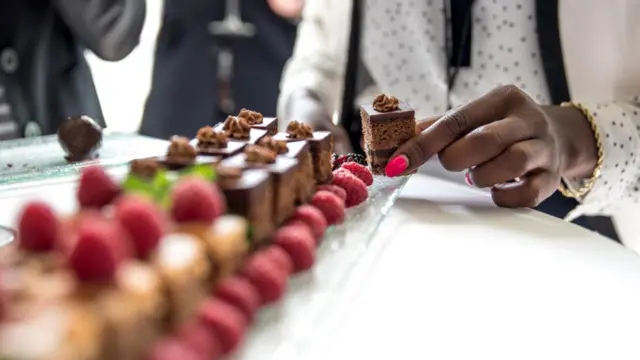 Seorang perempuan mengambil kue di perjamuan.