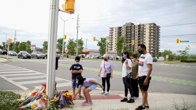 Personas se acercan a dejar flores a un homenaje en plena calle en Ontario, Canadá.