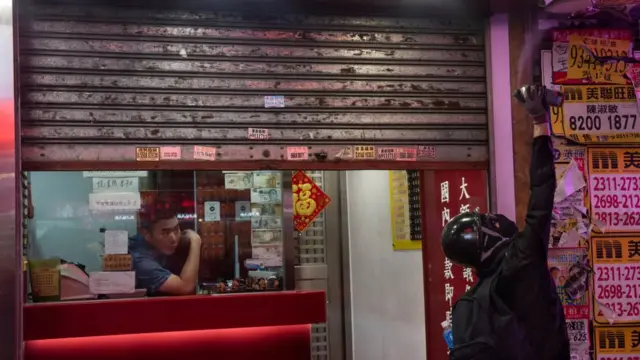 অব্যাহত বিক্ষোভে উদ্বিগ্ন হয়ে পড়ছেন ছোট-বড় সব ব্যবসায়ী। দোকানের শাটার অর্ধেক বন্ধ। দোকানের নিরাপত্তা ক্যামেরায় কালি স্প্রে করছে এক বিক্ষোভকারী।