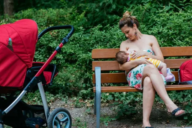 Ibu menyusui anaknya di sebuah pusat keramaian.