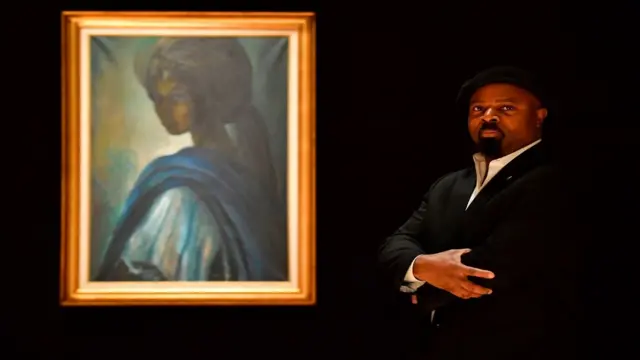 L'écrivain nigérian Ben Okri pose avec une œuvre d'art du peintre et sculpteur nigérian Ben Enwonwu intitulée 'Tutu'