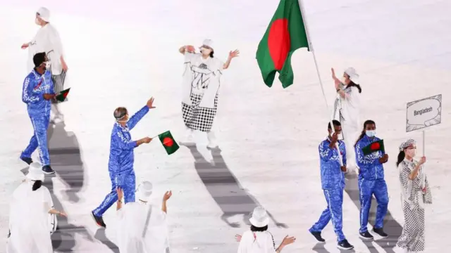 টোকিও অলিম্পিকের উদ্বোধনীতে জাতীয় পতাকা হাতে বাংলাদেশ দল। চারটি ইভেন্টে ছয়জন অ্যাথলেট রয়েছেন বাংলাদেশ দলে।