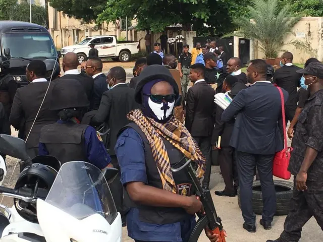 Security personnel carry gun among crowd