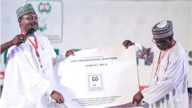 Alaga ajọ INEC ati eeyan kan n wo iwe idibo aarẹ