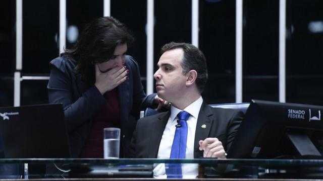 Simone Tebet conversa com Rodrigo Pacheco. Ele está sentado na Mesa do Senado e ela estáesportenet bet compé curvando-se para falar com ele, com a mão sobre a boca