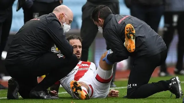 Southampton striker Danny Ings receives treatment from two physios after injuring his left knee against Aston Villa
