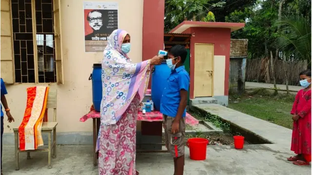 স্কুলে প্রবেশের আগে শিক্ষার্থীদের দেহের তাপ মাপা হচ্ছে।