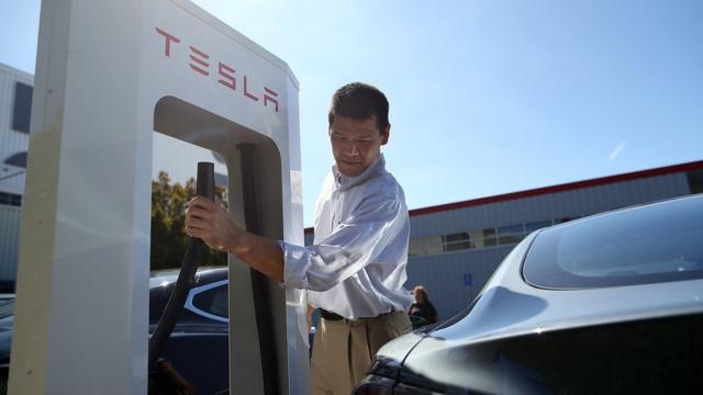 A man prepares to plug into a Tesla charging station in Fremont, California