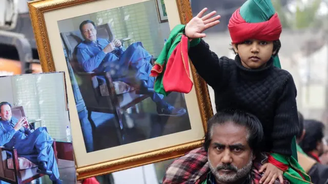رجل وابنه يرفعون صور رئيس الوزراء السابق عمران خان