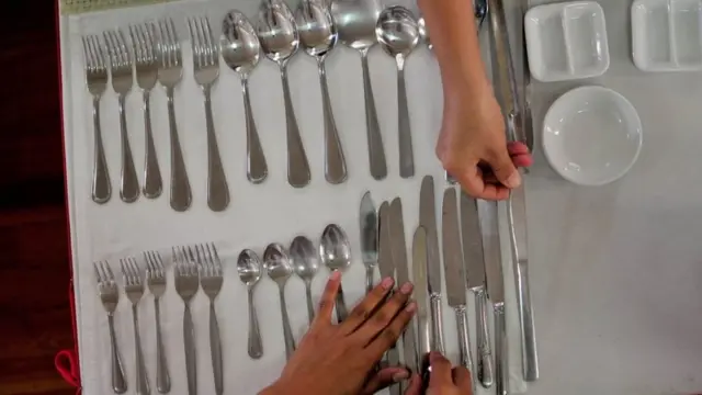 Mujer ordena los cubiertos en una mesa