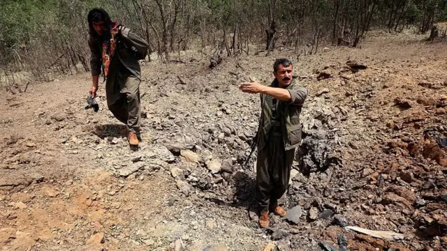 مقاتلون من حزب العمال الكردستاني (PKK) يتفقدون آثار القصف التركي عبى جبل قنديل
