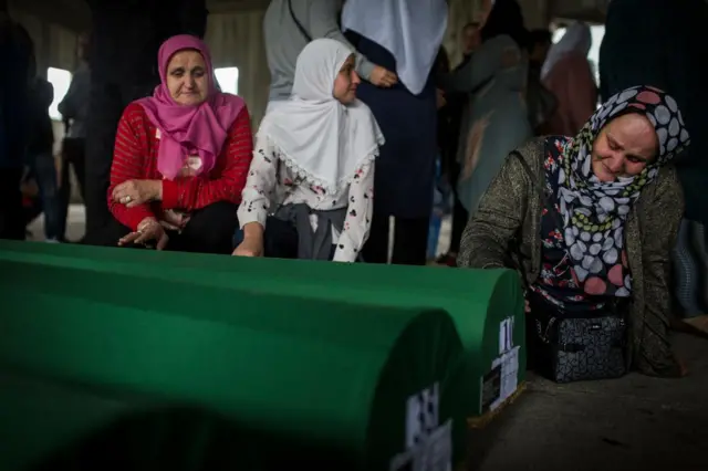 Uplakane žene pored tabuta