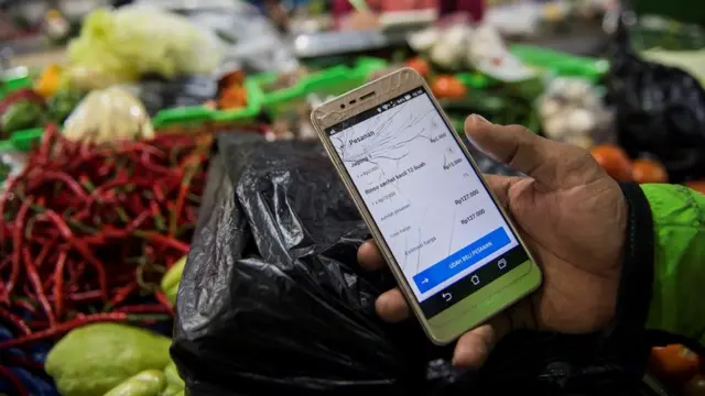 Pengemudi ojek menunjukan pesanan belanja daring di pasar Kosambi, Bandung, Jawa Barat, Jumat (10/4/2020)