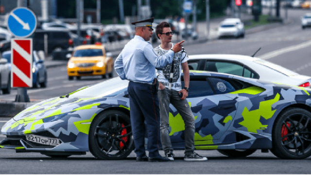 Maksim Yakubets fala com policialjogo mega wheelfrente a um Lamborghini