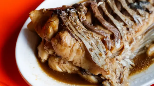 Тушеный карп на тарелке с соусом